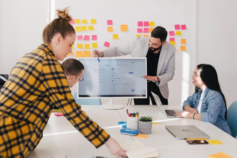 A management analyst gives a presentation to a group using a large monitor