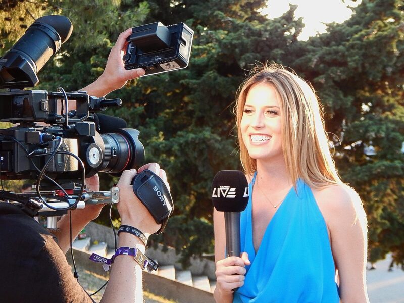 woman standing with microphone in front of reporters 