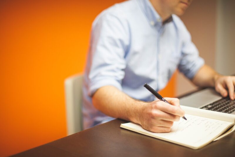man writing on notebook