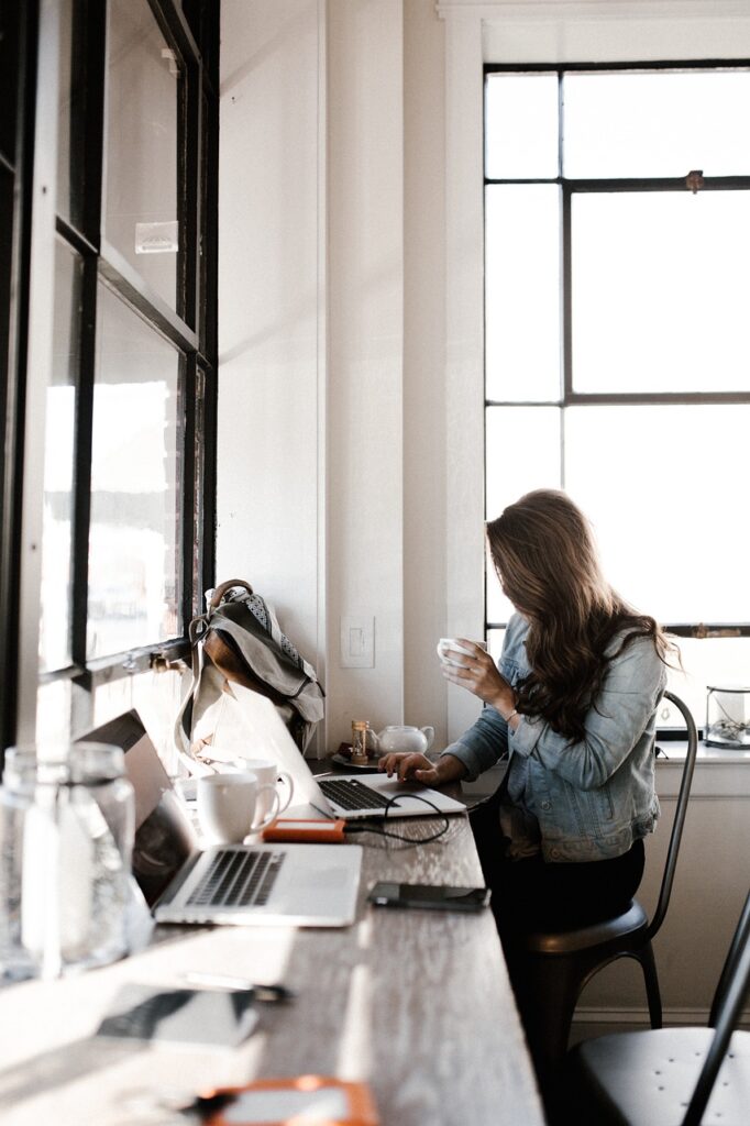 woman sitting at desk typing on computer, writing career example 