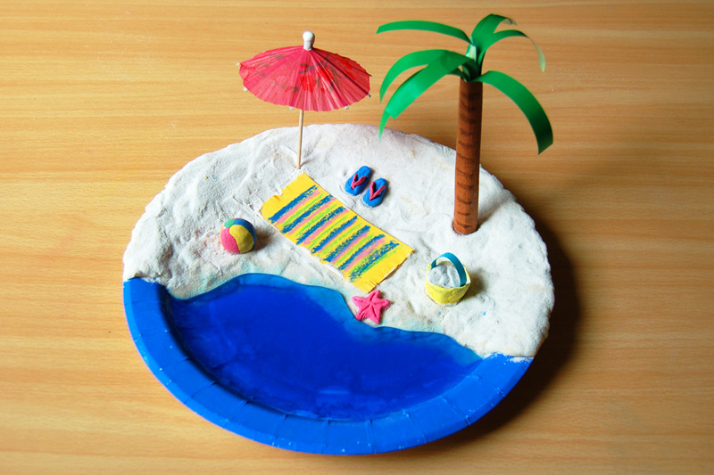 beachscene clay has been used to create sand on a paper plate. The ocean is painted blue. Various beach scene items have been added like a palm tree, umbrella, etc. (ocean activities)
