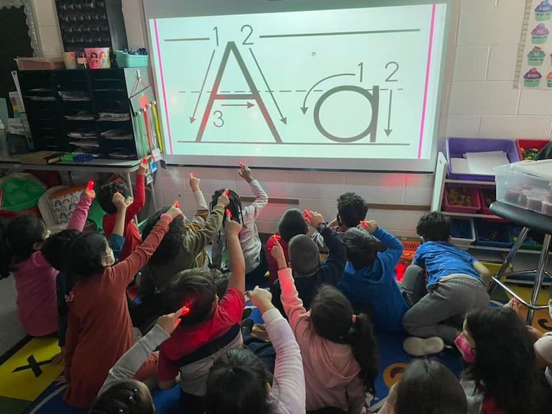 Kids enjoying Flashlight Friday Young students using finger flashlights to trace letters