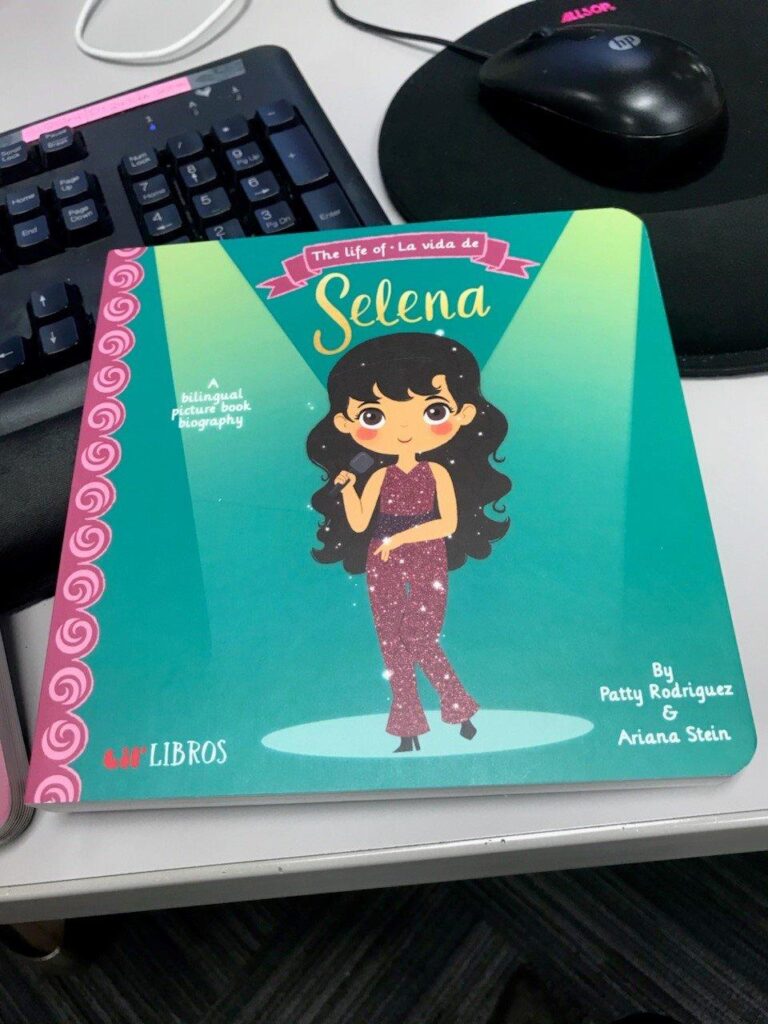 Selena Book Selena board book on top of computer keyboard.