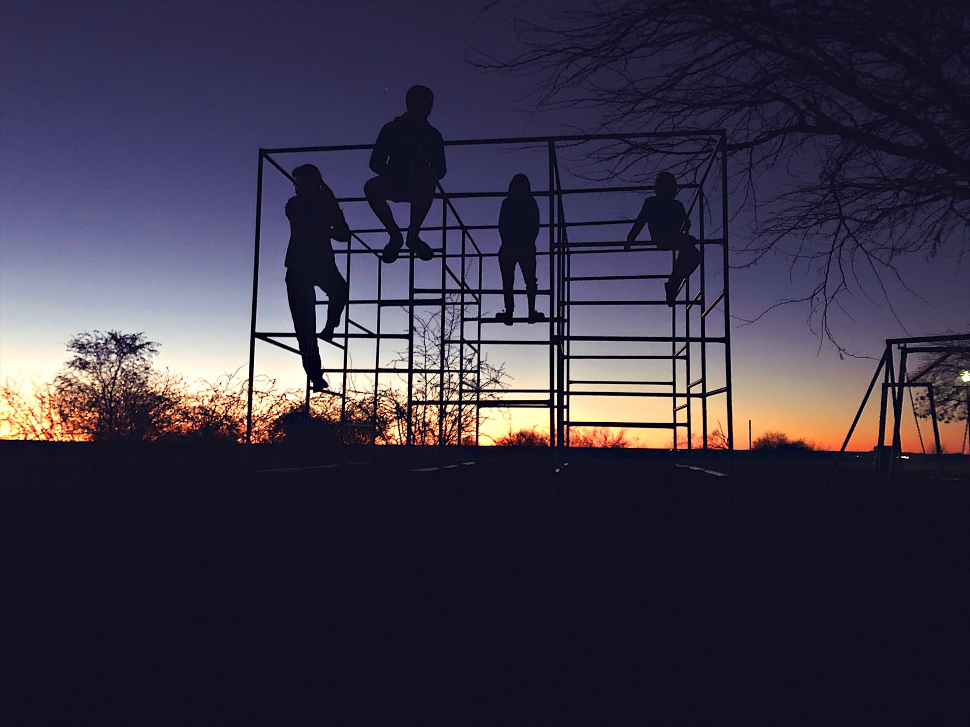Picture Writing Prompts: Sunset Friends Silhouette of 4 teenage and young children on a playground jungle gym tower at dawn in Namibia Africa