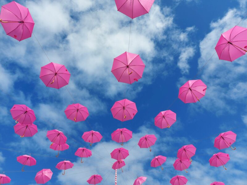 Writing Prompts: Pink Umbrellas Open pink umbrellas suspended against a blue sky with white clouds
