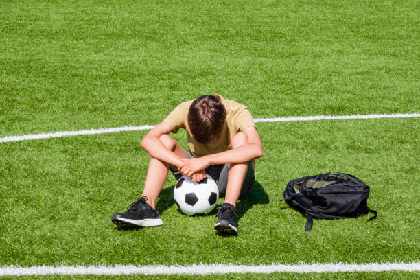 boy_with_soccer_ball Teenage boy sitting on soccer field