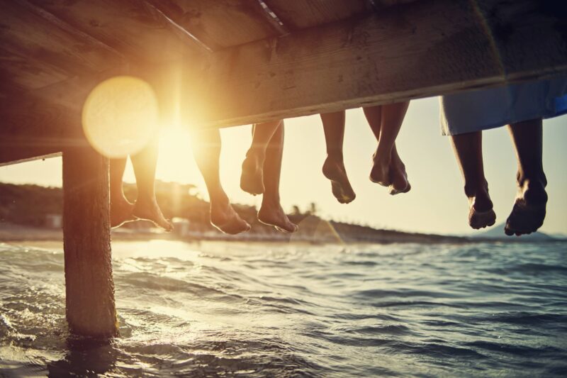 Picture Writing Prompts: Pier Sunset Five people having fun sitting on pier. Feet shot from below the pier. Sunny summer day evening.