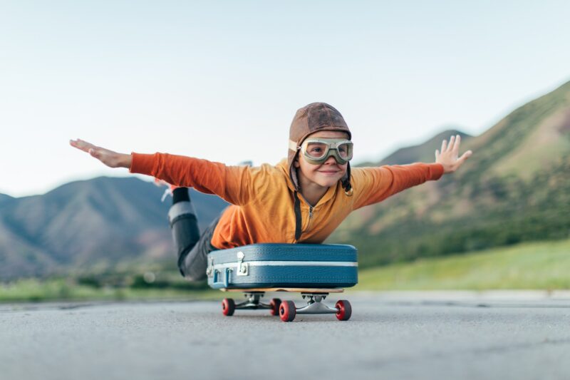 Picture Writing Prompts: Flying Boy A young boy wearing flying goggles and flight cap has packed his suitcase and has placed it on a skateboard. He is ready to fly away with arms outstretched to the destination of his dreams.
