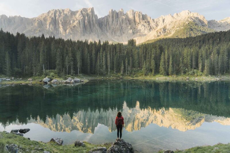 Picture Writing Prompts: Mountain Air Young Caucasian woman standing and looking at Lago di Carezza in Dolomites