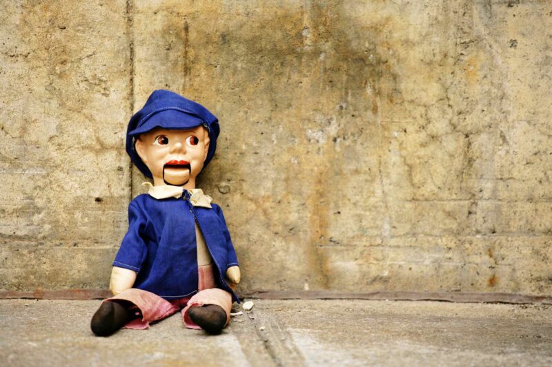 Picture Writing Prompts: Dummy Ventriloquist Dummy Sitting Against Concrete Wall
