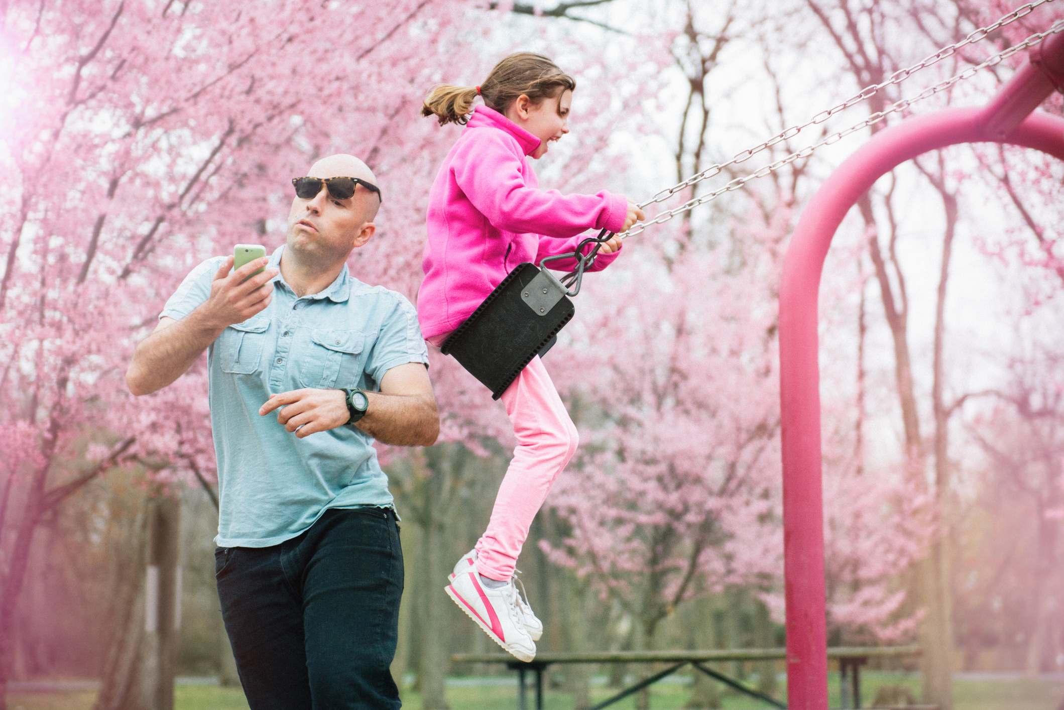 Writing Prompts: Swinging Parent gets hit by his daughter on the swing while watching smart phone.