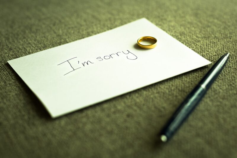 Picture Prompts: I’m Sorry A written paper note text written I'm sorry with a gold wedding ring left on top of it, and pen at home