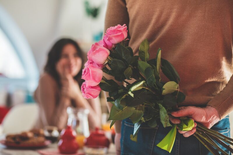 Picture Prompts: Ever After Close up shot of unrecognizable male holding a bouquet of roses behind his back, about to surprise his girlfriend.