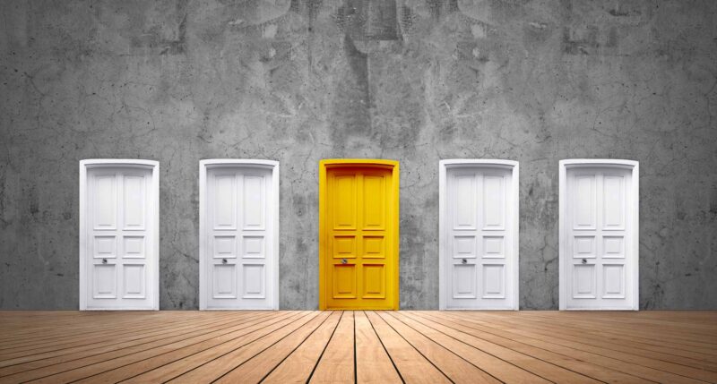 Picture Writing Prompts: Yellow Door A cement wall with a row of five doors. Four are white, but the one in the middle is yellow.
