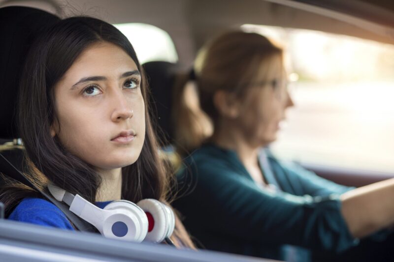 Picture Prompts: No One Understands A teen with headphones around her neck rolls her eyes and looks out the window while her mother drives