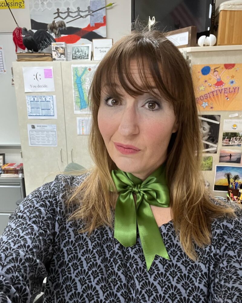 Teacher wearing a green ribbon bow around her neck