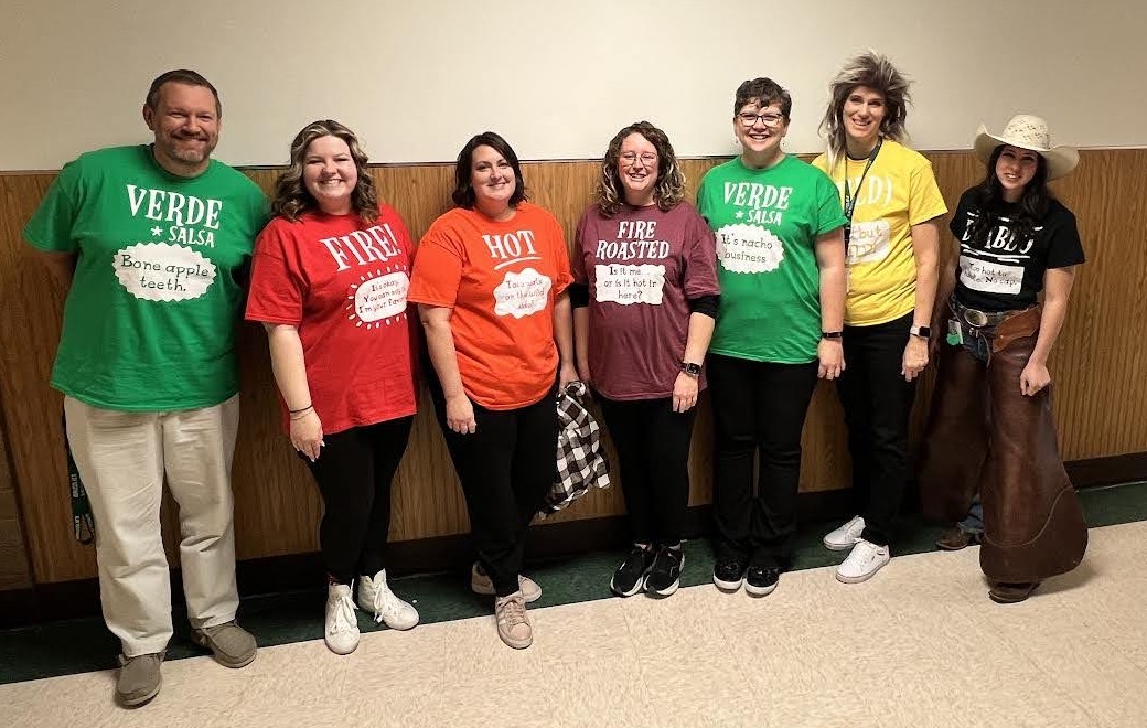 Group of teachers dressed in t-shirts that have Taco Bell sauce logos on them