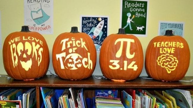 Carved pumpkins lined up on top of a bookshelf