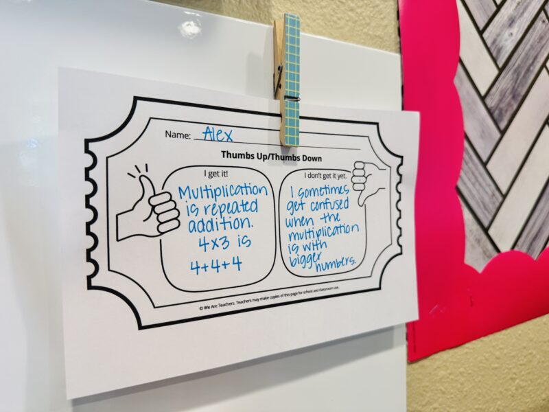 a thumbs up and thumbs down exit ticket hung up on a classroom whiteboard