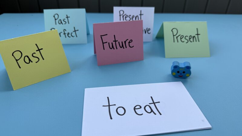 Colorful pieces of paper with verbs written on them propped up like tents